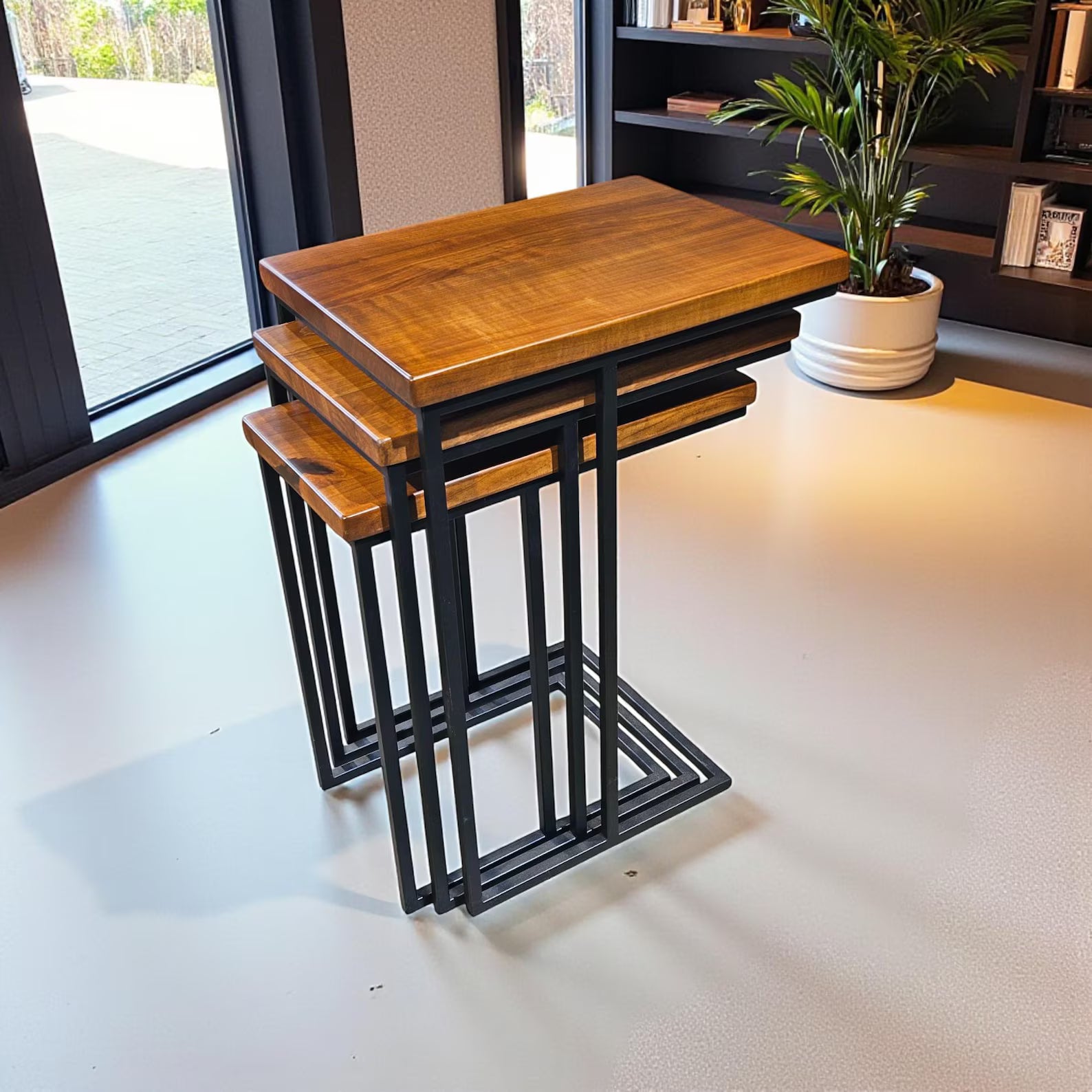 Set of three wooden nesting tables with black metal legs in a room setting.