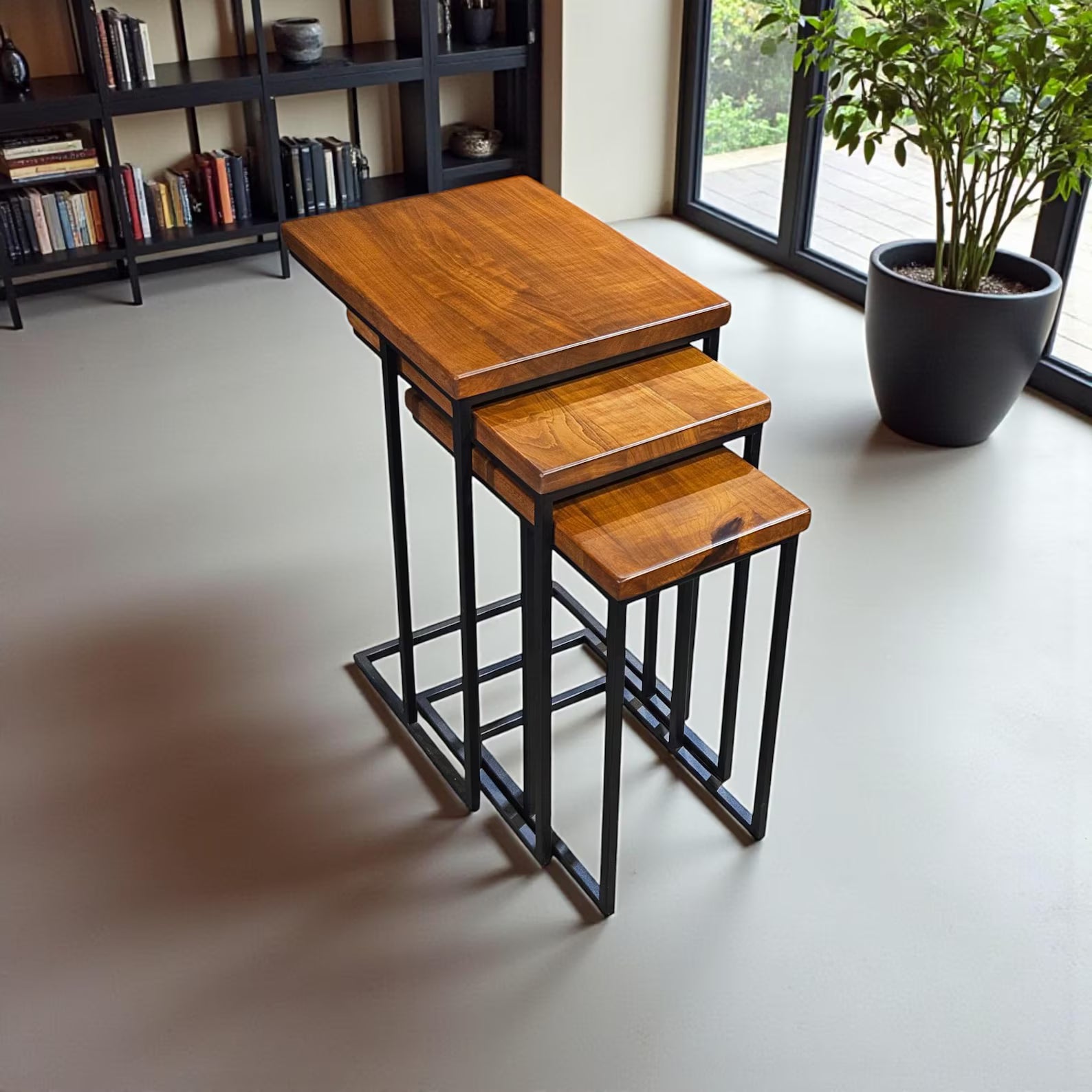 Set of three wooden nesting tables with black metal legs in a room setting.