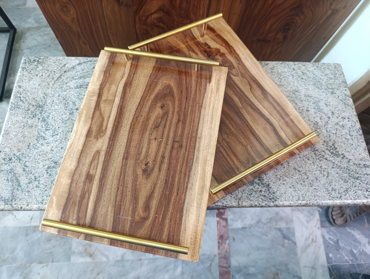 Two wooden cutting boards with gold handles on a marble surface.