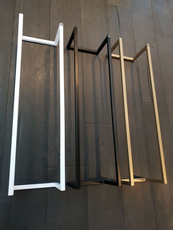 Three metal frames in white, black, and gold on a wooden floor.
