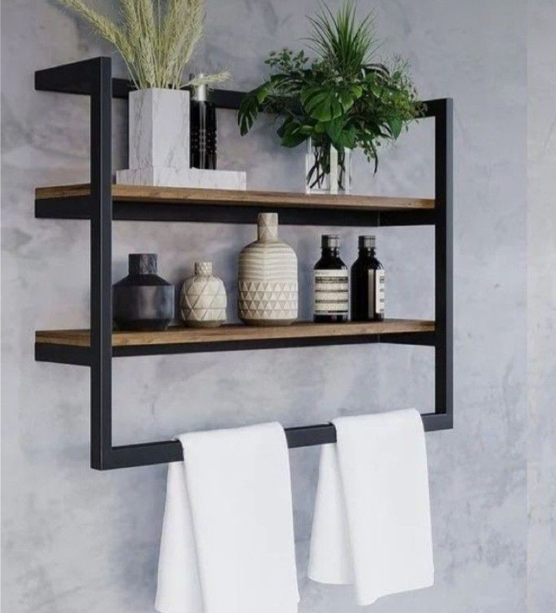 Wall-mounted shelf with wooden shelves and metal brackets, holding decorative items and towels.