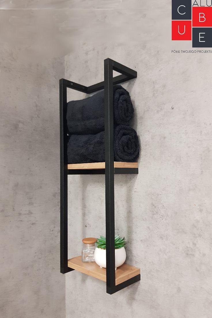Wall-mounted shelf with black metal frame and wooden shelves holding towels and small plants against a gray concrete wall.